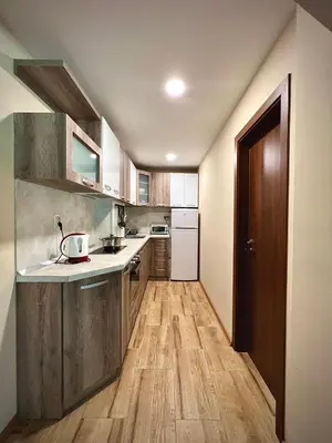 a kitchen with wooden cabinets and a wooden floor at RELAX aпартаменти, Смолянски езера, вила ВЕНЕРА, к-с Маунтин Лейк in Smolyan