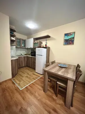 a kitchen with a wooden table and a white refrigerator at RELAX aпартаменти, Смолянски езера, вила ВЕНЕРА, к-с Маунтин Лейк in Smolyan