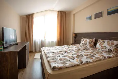 a bedroom with a large bed and a television at Guest house Legeto in Samokov