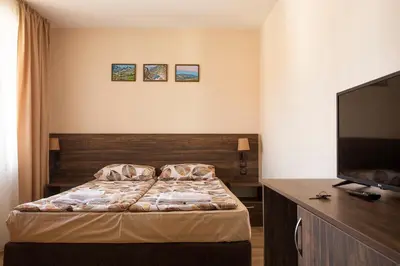 a bedroom with a bed and a flat screen tv at Guest house Legeto in Samokov