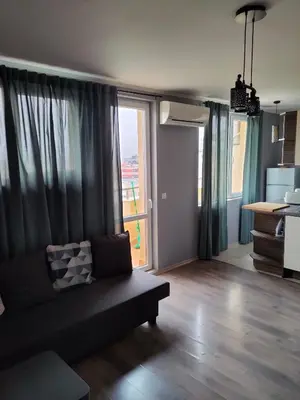 a living room with a couch and a large window at Mladost 1 Apartment near the metro in Sofia