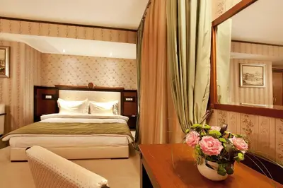 a hotel room with a bed and a desk with a table at Best Western Plus Bristol Hotel in Sofia