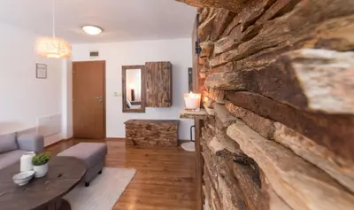 a living room with a large stone wall at ★ Chic & Elegant 1 Bedroom in Eagle's Nest Complex ★ Close to Gondola and Bar Street in Bansko