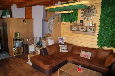 a living room with a brown couch and a clock at Roots Apartment in Borovets