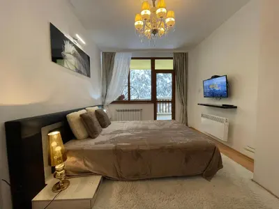 a bedroom with a large bed and a chandelier at Borovets Mountain Apartment Sequoia in Borovets