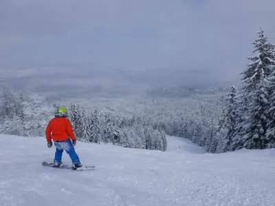 a man riding a snowboard down a snow covered slope at Borovets Apartment, Villa Park in Borovets