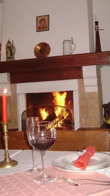 a table with a glass of wine and a fireplace at Bella Vista Guesthouse in Bansko