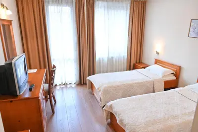 a hotel room with two beds and a television at Bella Vista Guesthouse in Bansko