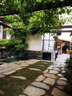 a stone patio with a fireplace in front of a house at Ikonomov House in Bansko