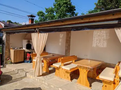 a wooden table and chairs under a pavilion at Family Hotel Velevi in Velingrad