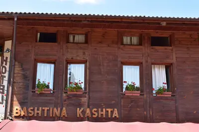 a wooden building with windows with flowers on it at Family Hotel Bashtina Kashta in Koprivshtitsa