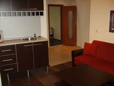 a living room with a red couch and a kitchen at Hotel Trakart Residence in Plovdiv