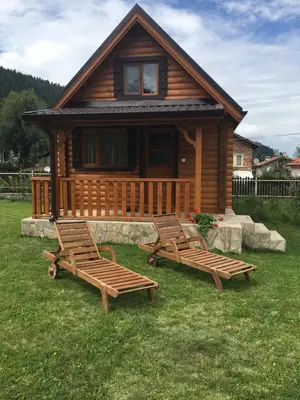 two chairs in front of a log cabin at Еднофамилна дървена къщичка in Beli Iskar