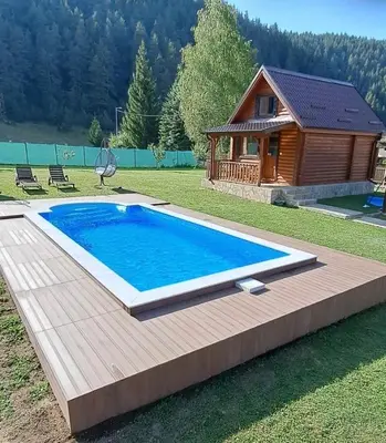 a swimming pool in front of a log house at Еднофамилна дървена къщичка in Beli Iskar
