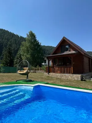 a blue swimming pool in front of a house at Еднофамилна дървена къщичка in Beli Iskar