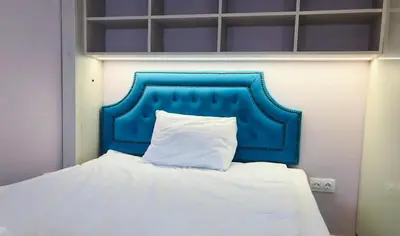 a bed with a blue headboard and a white pillow at Bluemarine Apartment in Sofia