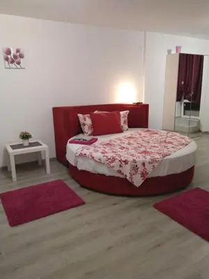 a bedroom with a large bed with red sheets and red rugs at Sofia Peak in Sofia