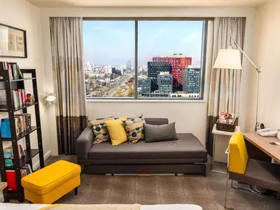 a living room with a couch and a large window at Novotel Sofia in Sofia