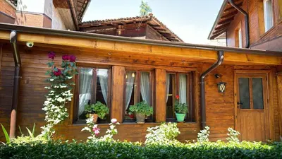 a wooden house with potted plants on the windows at Guest House Roden Dom in Koprivshtitsa