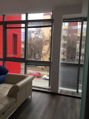 a living room with a couch and a large window at Lilia 2 Self-Check in apartment in Sofia