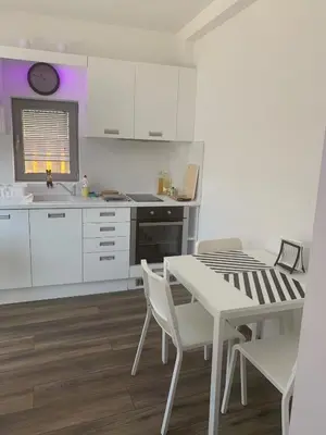a kitchen with white cabinets and a table and chairs at Lilia 2 Self-Check in apartment in Sofia