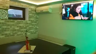 a room with a tv on a wall with a table at Sharkova House Bansko in Bansko