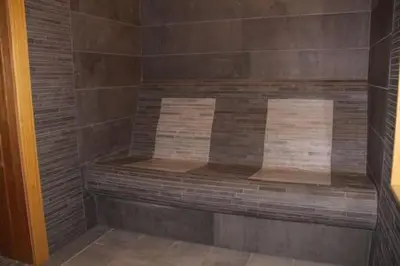 a wooden bench in a shower with brown tiles at 7 Pools SPA Boutique Hotel in Bansko