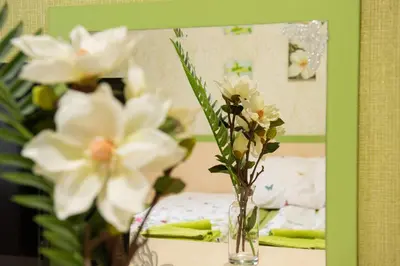 a vase of flowers on a table in front of a mirror at Family Hotel Enica in Teteven