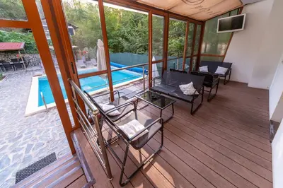 a screened in porch with chairs and a pool at Villa Drecheva in Ognyanovo