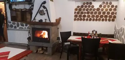 a dining room with a fireplace and a table and chairs at Guest House Planinski Zdravets in Bansko