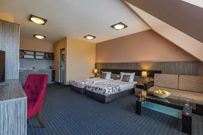 a hotel room with a bed and a red chair at Plaza Hotel Plovdiv - Free Parking in Plovdiv
