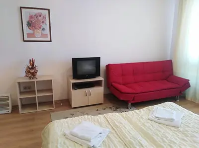 a living room with a red couch and a tv at Aspen golf studio apartment D208 in Razlog