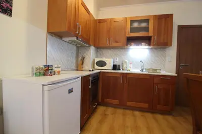 a kitchen with wooden cabinets and a white refrigerator at Pine Tree Apartment 3 - B3 in Bansko