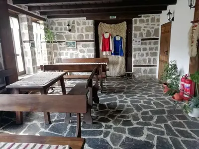 a room with wooden tables and benches on a stone floor at Family Hotel Kalifer in Kalofer