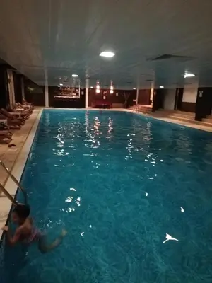 a person swimming in a large swimming pool at Grand Monastery - Azure Apartment in Pamporovo
