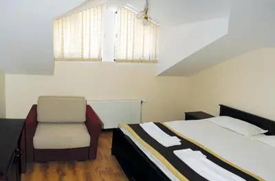 a bedroom with a bed and a chair at СТАИ ЗА ГОСТИ в КЪЩА КАМЕЛИЯ in Pamporovo