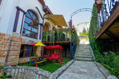 a building with a table and an umbrella in the yard at Boutique & Spa Hotel Heaven in Velingrad