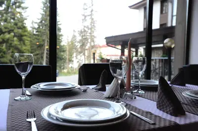 a table with plates and wine glasses on a table at Hotel Mursalitsa by HMG - Half board in Pamporovo