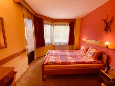 a bedroom with a bed with orange walls at Family Hotel Savov in Chepelare