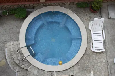 a swimming pool with a chair and a ball in it at Guest House Tabakovi in Velingrad