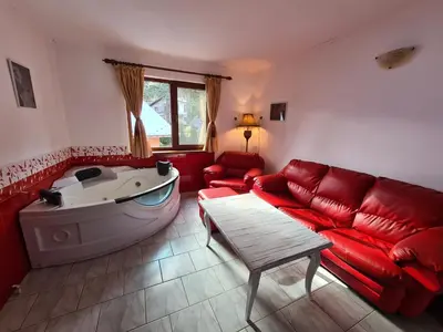 a living room with a red couch and a tub at Vila Kalvachevi in Tsigov Chark
