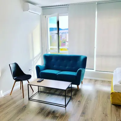a living room with a blue couch and a table at Turquoise and Magenta Apartment in Sofia
