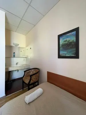 a bedroom with a bed and a chair and a painting at Rooms Sonata in Kyustendil