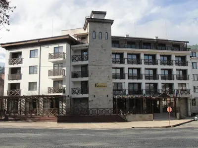 a white building with a clock tower in front of it at Spa Hotel Kleptuza in Velingrad
