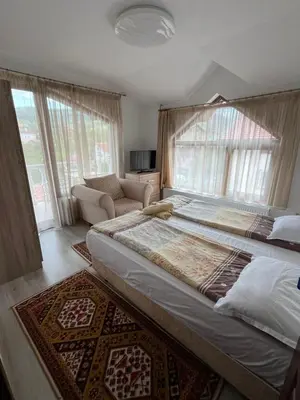 a bedroom with a large bed and a couch at Bayrakova Guest House in Dobrinishte