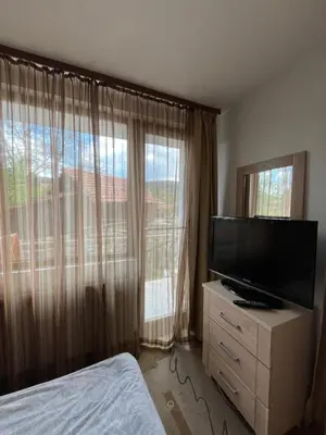 a bedroom with a flat screen tv and a large window at Bayrakova Guest House in Dobrinishte