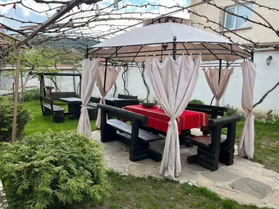 a picnic table under a gazebo with a red table at Bayrakova Guest House in Dobrinishte