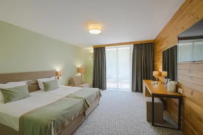 a hotel room with a large bed and a desk at Spa Hotel Orbita in Blagoevgrad