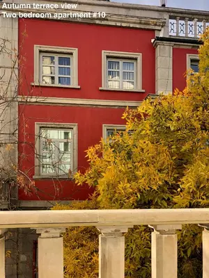 a red building with white windows and bushes in front at SKYLER GUEST HOUSE in Plovdiv
