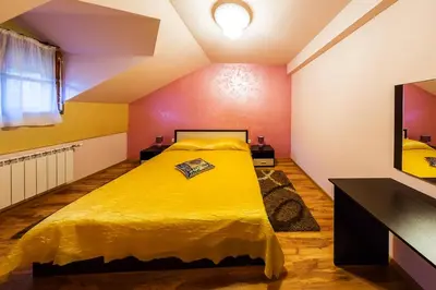 a bedroom with a yellow bed and a tv at Family Hotel Ogi in Asenovgrad